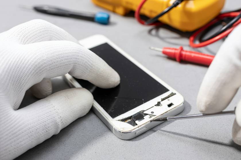 Technician hands working on broken smartphone for repair or replace new part on desk